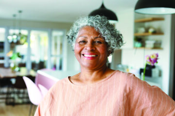 Older adult enjoying life in an independent living community, sitting outdoors with a smile, showcasing the benefits of socialization and comfort in senior living