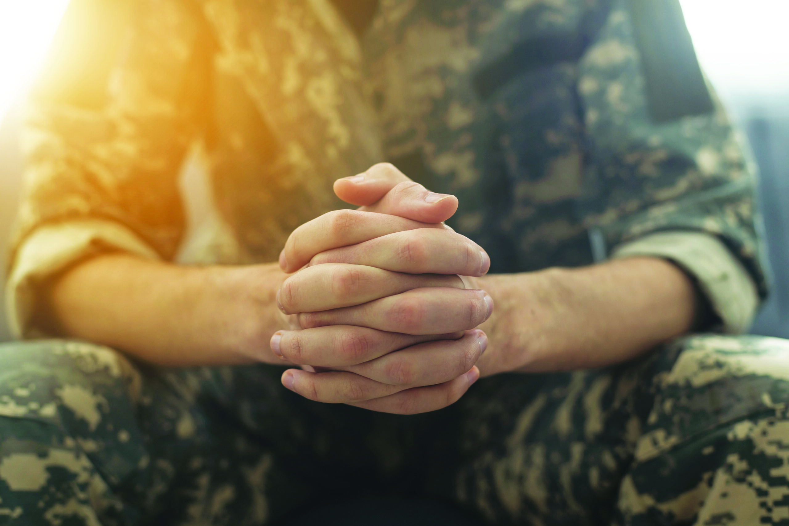 Veteran in uniform sitting with hands clasped, reflecting on the challenges of seeking help, symbolizing the inner struggle many face in accessing care and support.