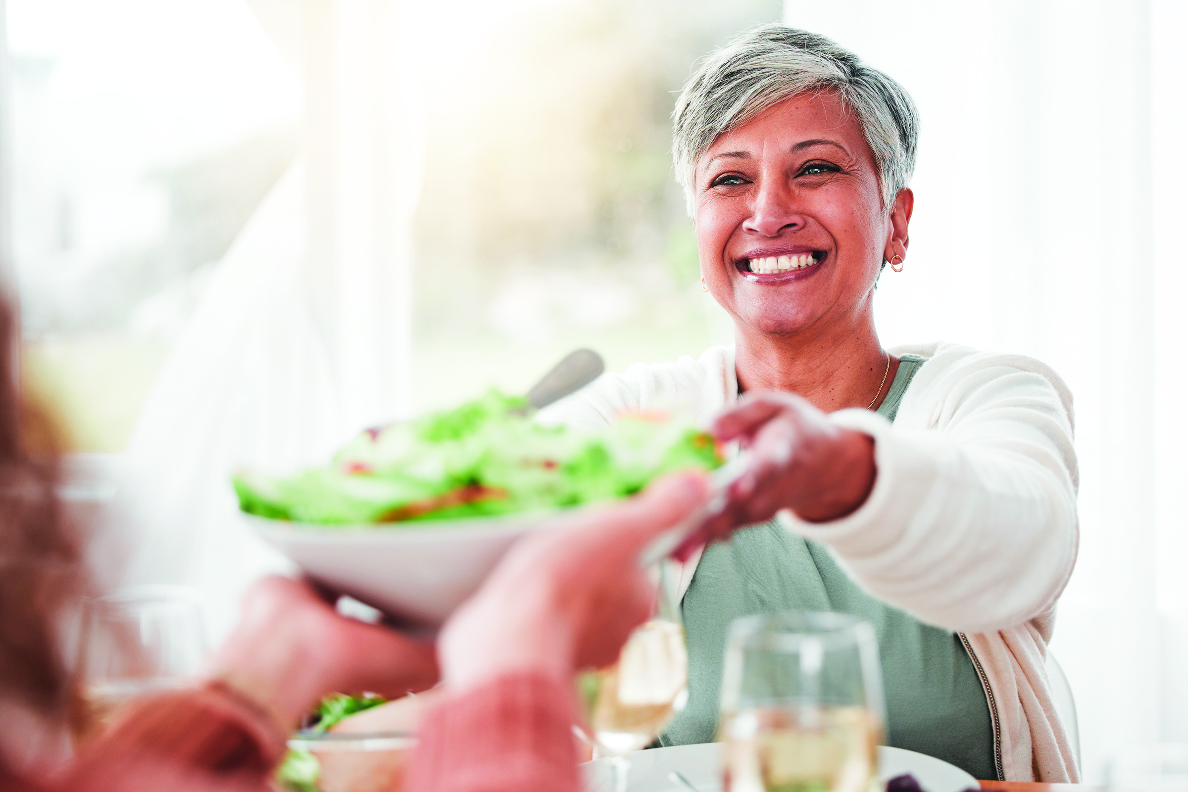 Older woman happily receiving a bowl of salad from a server, highlighting the importance of a nutritious diet for healthy aging