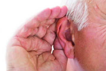 Older man holding his hand to his ear, trying to hear better, illustrating the challenges of hearing loss in seniors