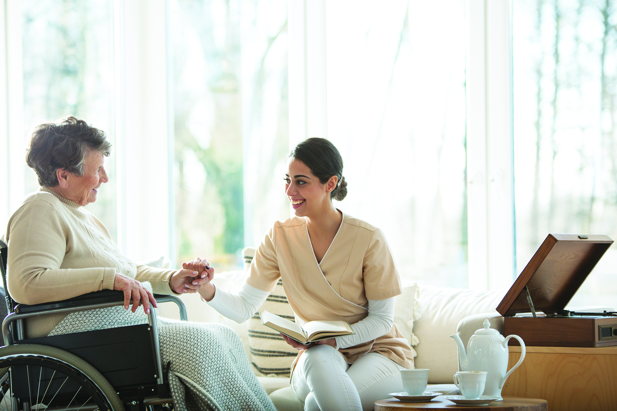 Hospice care provider comforts an elderly woman in a wheelchair.